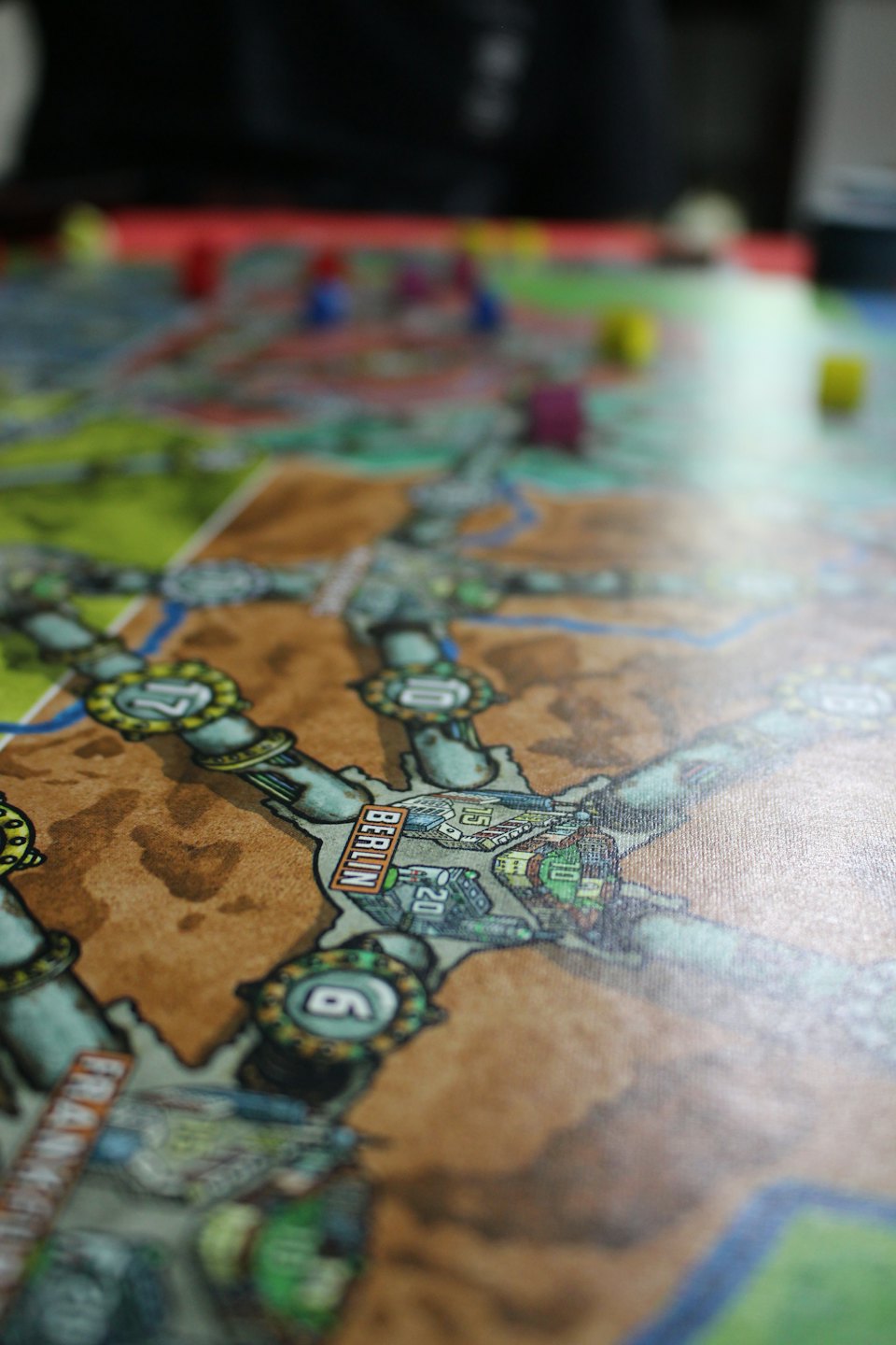 Des pièces de jeu colorées sont posées sur une carte de jeu de société complexe.
